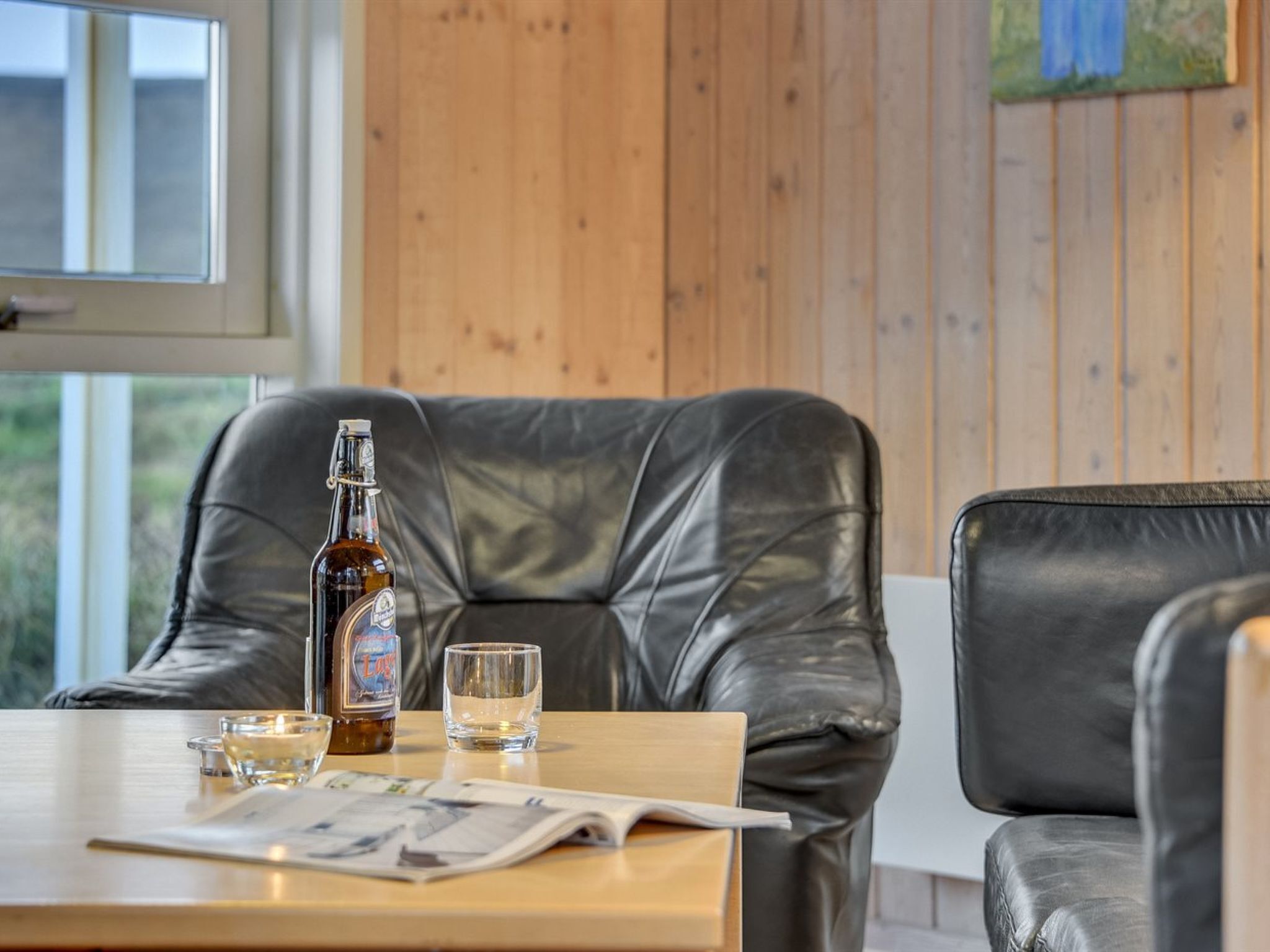 Ein ledernes Sofa, ein Tisch mit einer Flasche, einem Glas und einer Speisekarte.