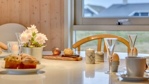 Une table de petit-déjeuner avec des viennoiseries, des œufs et un vase de fleurs.