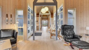 Un intérieur spacieux avec des murs en bois, un plafond haut et un espace central ouvert donnant sur un balcon.