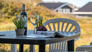 Une table avec une bouteille, deux verres, une plante en pot et un bol de cerises.
