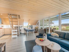 Um interior moderno com área de jantar, sofá e vista para o exterior.