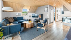 A modern loft-style living room with a sloped ceiling, a sofa, a coffee table, a chair, and a TV. - "Klimentina" - 150m from the sea by Interhome (Ringkøbing)