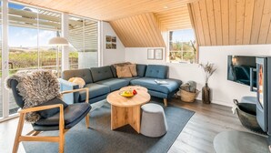 A modern loft-style living room with a large sectional sofa, a round wooden coffee table, and a television. - "Klimentina" - 150m from the sea by Interhome (Ringkøbing)