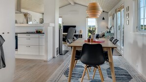 A modern dining area with a wooden table, black chairs, and a hanging light fixture.