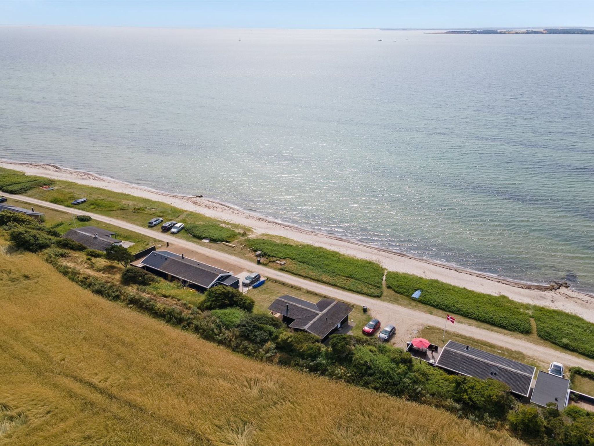 En fastighet vid kusten med flera hus, en strand och en väg som leder ner till havet.