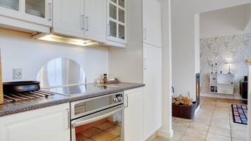 Una cucina moderna con pensili bianchi, una cappa in acciaio inossidabile e una parete rivestita di piastrelle.