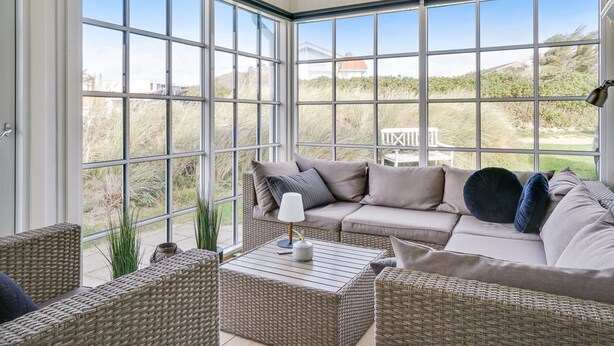 A sunroom with large windows, wicker furniture, and a view of the outdoors. - "Wiebke" - 200m from the sea by Interhome (Blokhus)