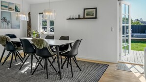 A dining area with a table and chairs, a hanging light fixture, and a view of the outdoors through a glass door. - "Wiebke" - 200m from the sea by Interhome (Blokhus)