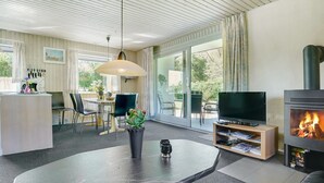A modern living room with a large table, a TV, and a fireplace.