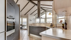 A modern kitchen with a large island, stainless steel appliances, and a view to the outside.