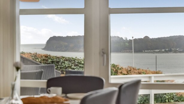 A dining area with a view of a body of water and a cliff.
