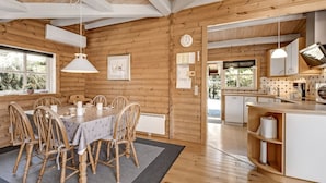 Ein Interieur einer Holzhütte mit Essbereich, Küche und Blick ins Freie.