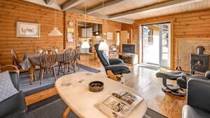 Ein gemütliches Blockhaus-Interieur mit Essbereich, Sitzgelegenheiten, Kamin und Fernseher.