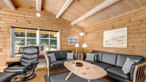 Ein gemütliches Blockhaushaus-Interieur mit einer Ledersofa, einem Esstisch und einem Ledersessel.