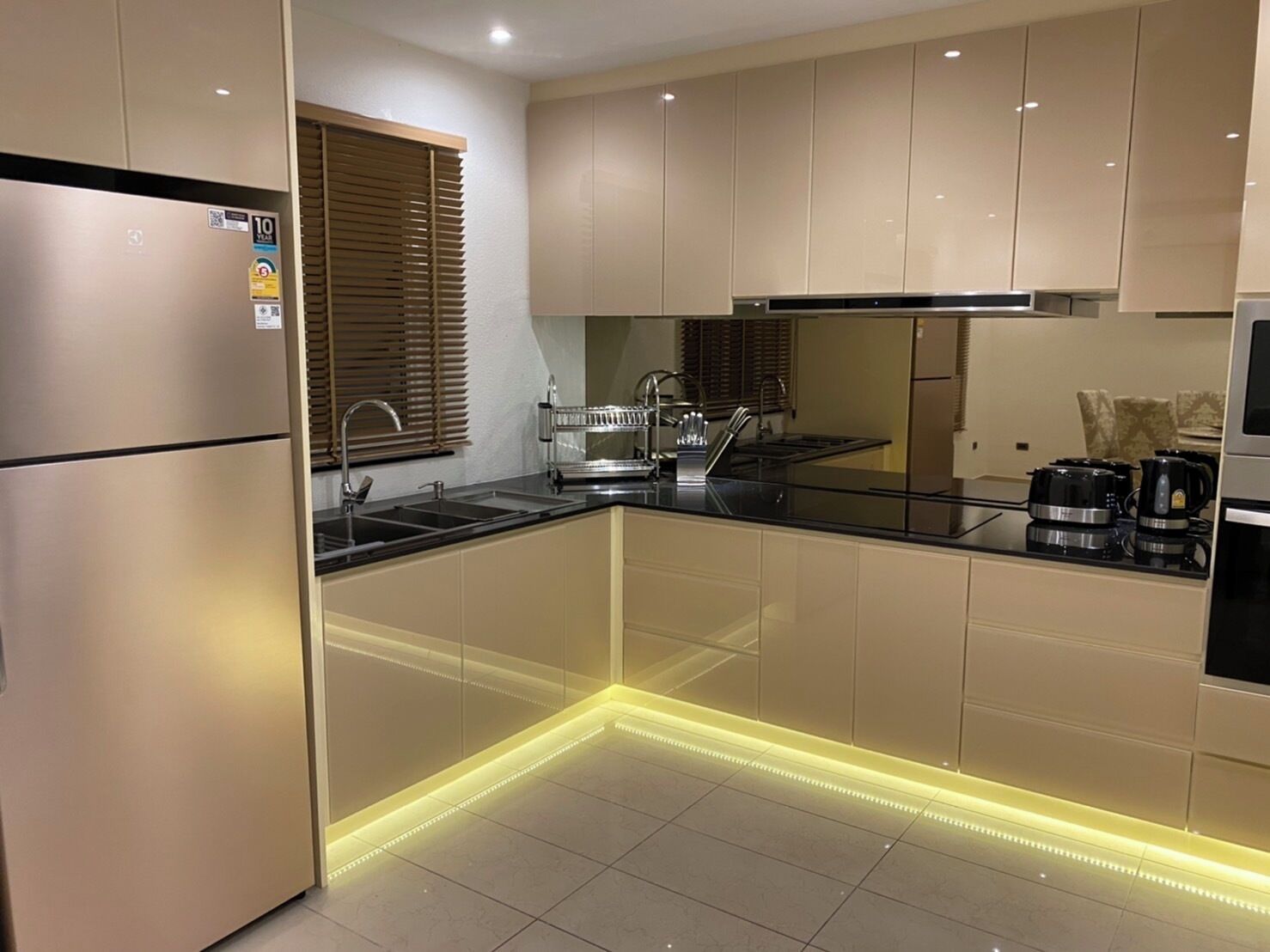 A modern kitchen with stainless steel appliances, a black countertop, and LED under-cabinet lighting.