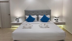 Una habitación de hotel con una cama grande, dos mesitas de noche y una puerta.