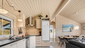A modern kitchen with a central island, a dining area with a view, and a living space with a sofa.