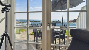 A room with a large window overlooking a patio with outdoor furniture and a view of the sea. - "Seba" - 500m from the sea by Interhome (Allinge)