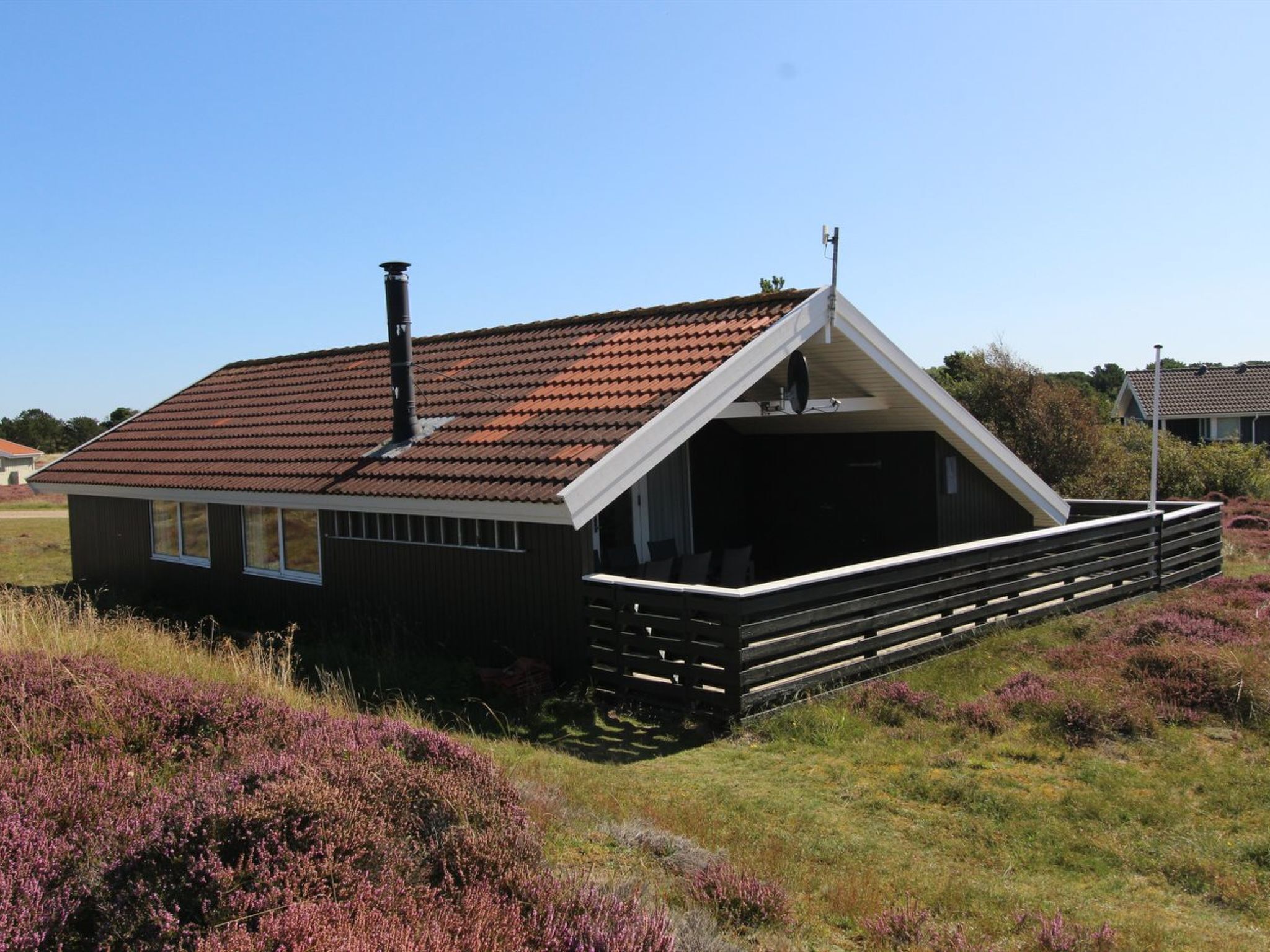 A modern house with a sloped roof, a chimney, and a covered porch area.