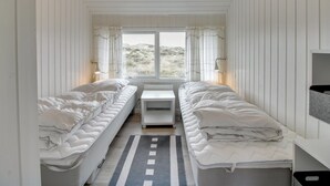 A compact room with two single beds, a small table, and a window providing a view of the outdoors. - "Lilja" - 1.5km from the sea by Interhome (Fanø)