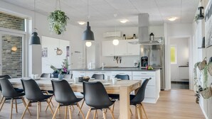 Et moderne køkken med en central ø, sorte stole og hængende planter.