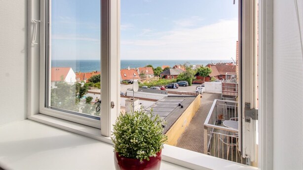 Een balkon met uitzicht op een woongebied en de zee.