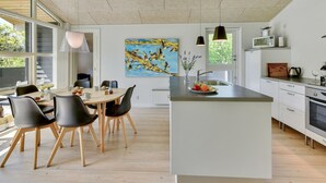 Une cuisine moderne dotée d’un îlot central, d’un coin repas avec des chaises et d’une grande fenêtre.