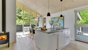 Une cuisine moderne dotée d’un îlot central, d’un éclairage suspendu et d’une grande fenêtre donnant sur une terrasse.