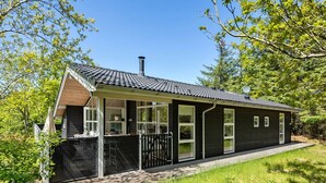 Une maison moderne avec un toit en pente, de grandes fenêtres et une cheminée.