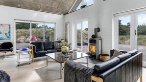 A modern living room with a glass coffee table, black leather sofa, and a stone fireplace.