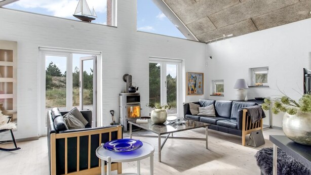 A spacious living area with a fireplace, a sofa, a coffee table, and a view of the outdoors.