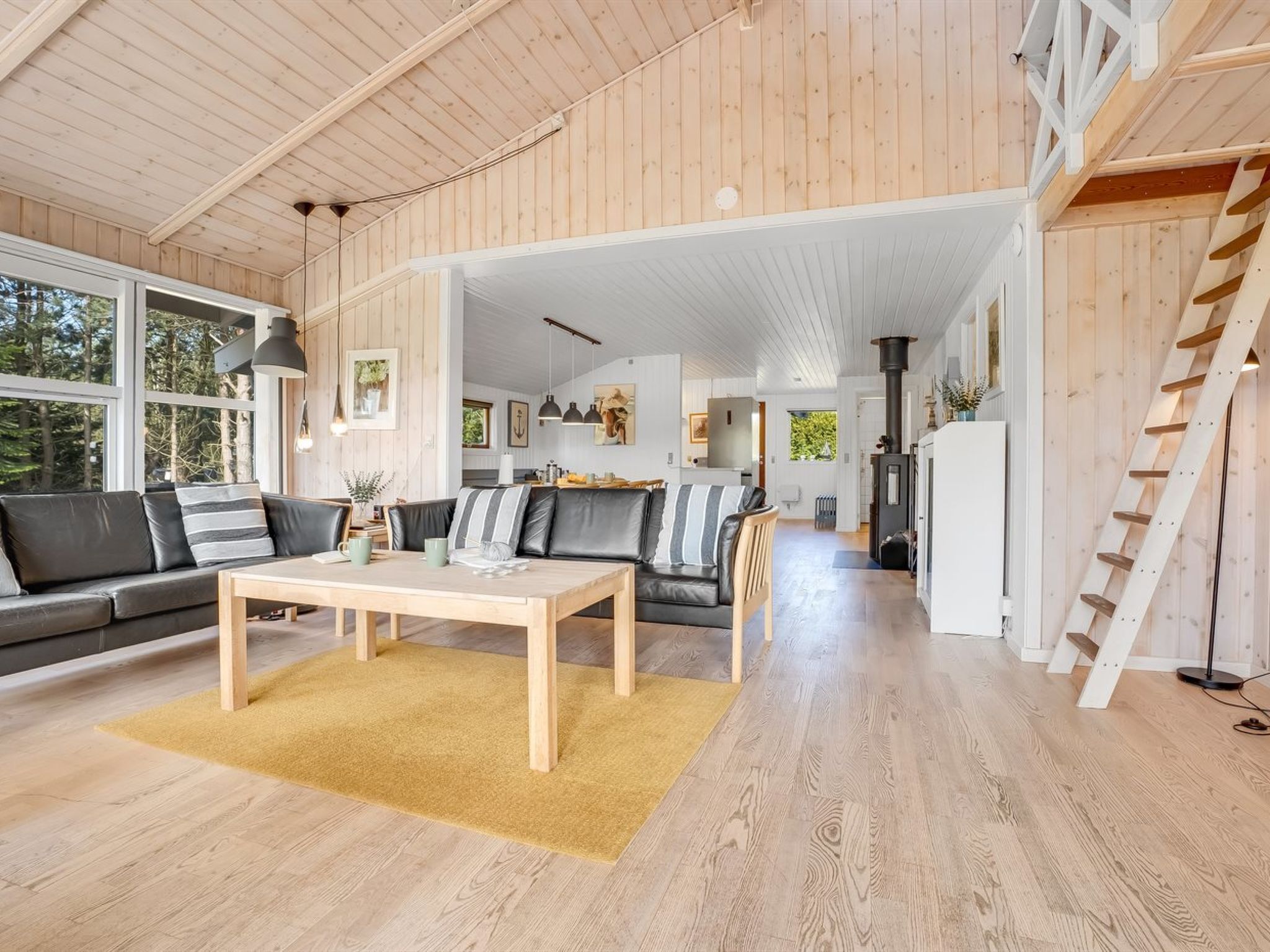 Ein geräumiges Wohnzimmer mit Holzboden, einer Sofagarnitur, einem Couchtisch und einer Treppe.