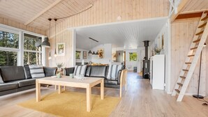 A spacious living room with a wooden floor, a sofa set, a coffee table, and a staircase.