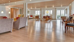 A spacious living area with wooden flooring, a dining table, and multiple seating arrangements.