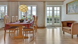 A dining area with a wooden table, chairs, and a hanging light fixture.