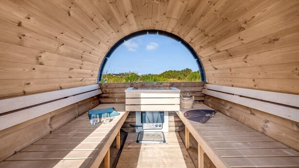 A sauna with wooden benches and a central heating unit, surrounded by a wooden arch structure. - "Teoline" - 500m to the fjord by Interhome (Hvide Sande)