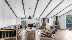A spacious living room with a sofa, a coffee table, and a rocking chair. There is a television and a fireplace. - "Teoline" - 500m to the fjord by Interhome (Hvide Sande)