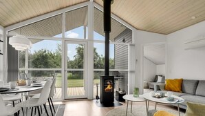 Un interior moderno con un amplio espacio abierto, una chimenea y un comedor con vistas al exterior.