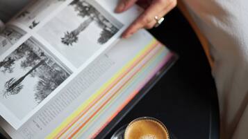 Una persona leyendo un libro con una taza de café sobre una mesa.