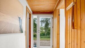 A hallway with wooden walls and a tiled floor leading to a glass door. - "Sverker" - 300m from the sea by Interhome (Rødby)