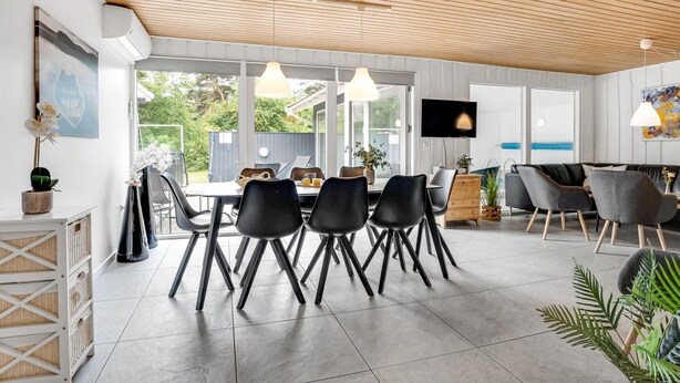 A modern kitchen with a large island, a dining area with black chairs, and a living area with a sofa and chairs. - "Sverker" - 300m from the sea by Interhome (Rødby)