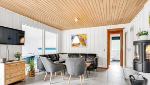 A modern living room with a wooden ceiling, a flat-screen TV, a sofa, chairs, a wooden dresser, and a fireplace. - "Sverker" - 300m from the sea by Interhome (Rødby)
