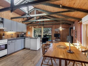 A spacious kitchen with modern appliances, a dining area with wooden furniture, and a cozy living space with a fireplace.