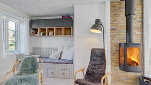 Een gezellige woonkamer met een open haard, een bank, een fauteuil en een boekenkast.