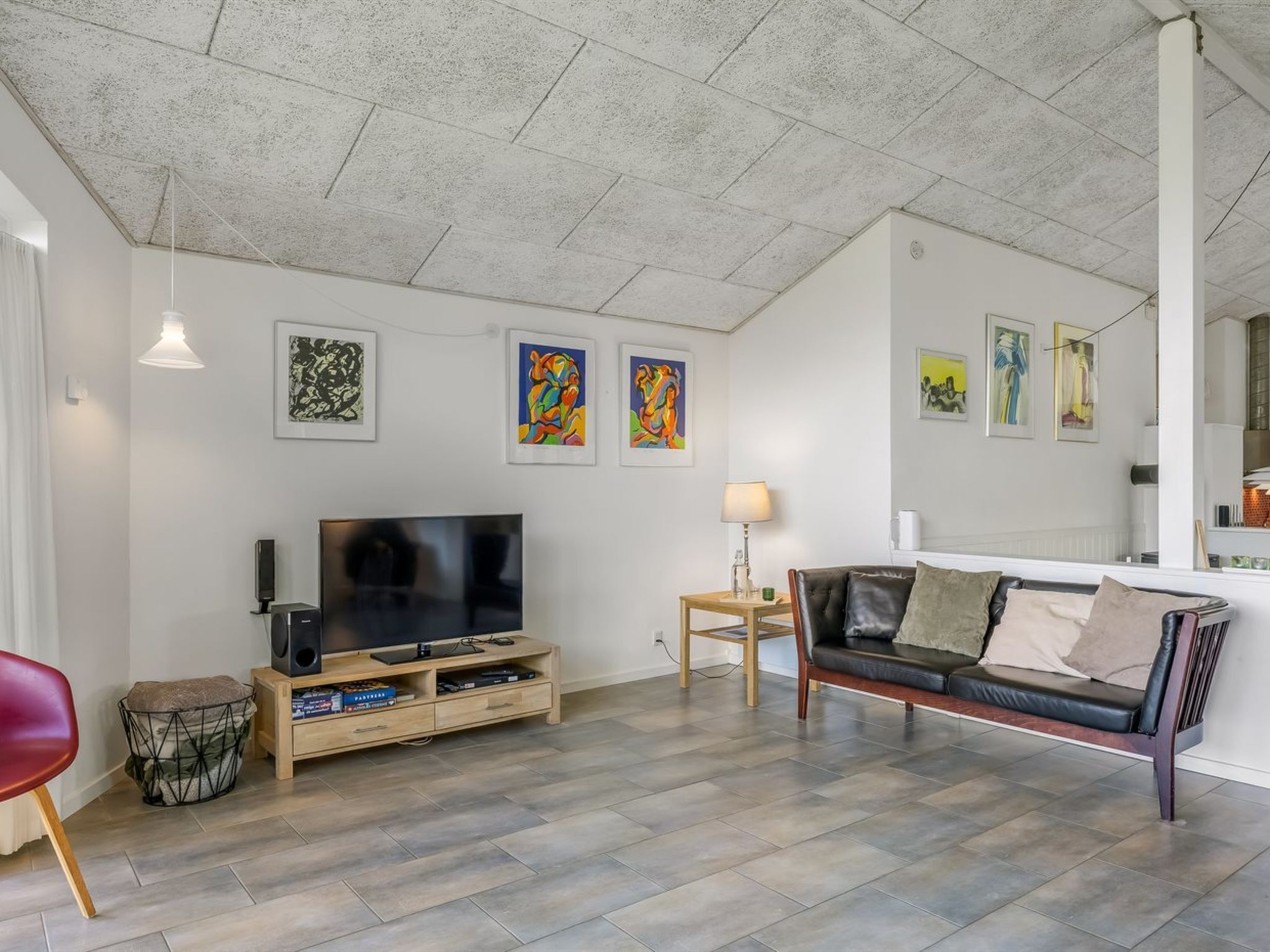 Un salon équipé d’un téléviseur à écran plat, d’un canapé, d’une table basse et agrémenté d’œuvres d’art aux murs.