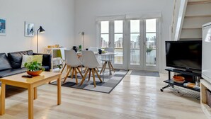 A modern living room with a sofa, dining table, chairs, a TV, and a balcony with large windows. - "Tofan" - 100m to the fjord by Interhome (Vestervig)