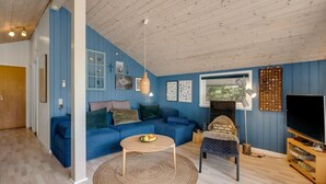 Un salon avec un canapé bleu, une table basse ronde, une cheminée et un téléviseur.