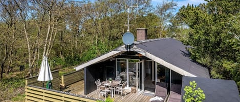 A modern cabin with a deck, outdoor seating, and a satellite dish.
