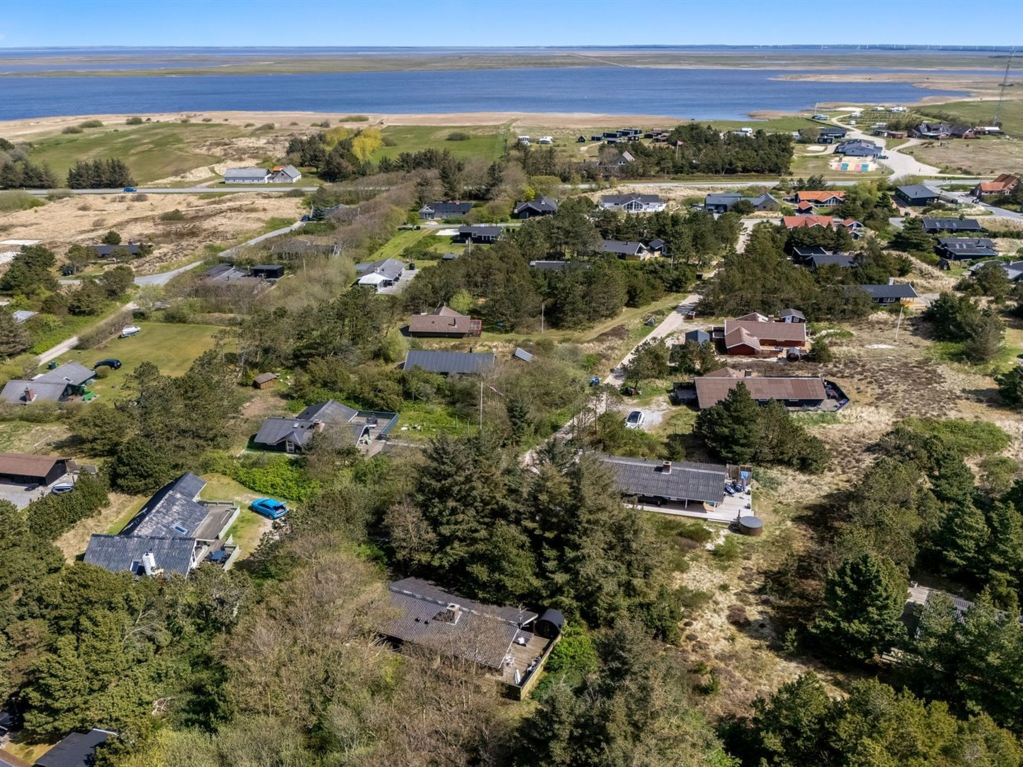 An aerial view of a residential area with houses, roads, and a body of water in the background.