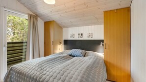 Une chambre à coucher avec un lit, une armoire en bois et une fenêtre avec des rideaux.